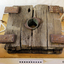 Wooden slide compressor mechanism has a central hole, and four rectangular metal plates fixed to the top.