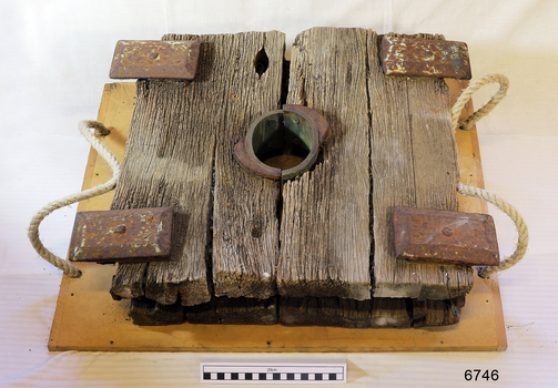 Wooden slide compressor mechanism has a central hole, and four rectangular metal plates fixed to the top.