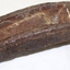 Iron piece is pitted and rusting. It is a curved shape with a formed channel along a portion of the centre