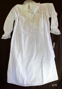 White garment with fancy yoke , neckline and sleeve cuffs