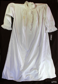 Long, white nightgown has long sleeves, round collar, front opening and lace trim
