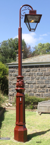 An old style gas lamp light on a wrought iron post.