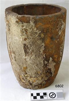 Grey clay has encrusted and orange-stained surface. Inscriptions are on the pot.