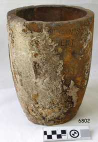 Grey clay has encrusted and orange-stained surface. Inscriptions are on the pot.