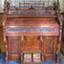 Wood encased organ with decorative fretwork and red and cream carpet-covered foot pedals