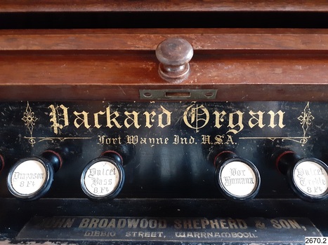 Maker's name and details, gold embossed onto panel above keys