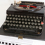 Remington typewriter with black and red ribbon installed, on its case's base