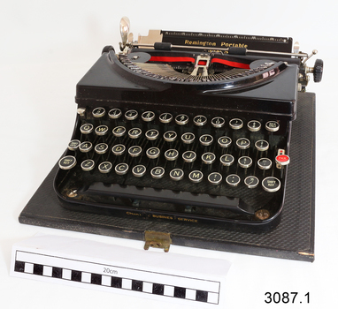 Remington typewriter with black and red ribbon installed, on its case's base