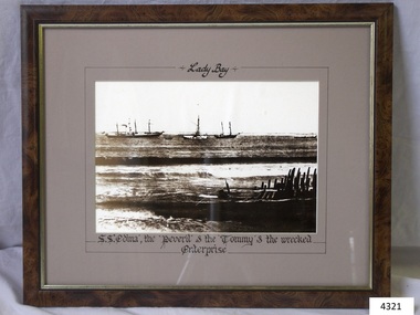 Sepia photograph in dark frame, behind glass, of vessels in the water.