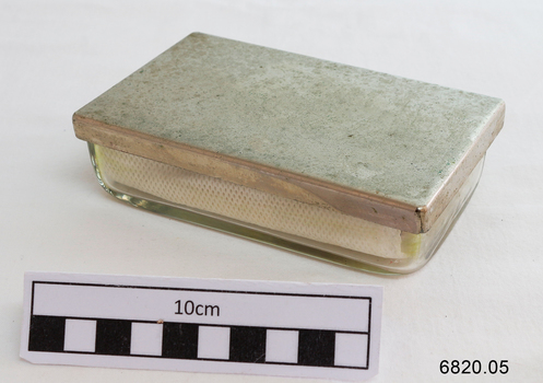 A small rectangular glass container with a metal lid 