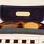 Orange rimmed glasses in blue case. One arm broken. Left lens blocked off with card. 