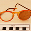 Orange rimmed glasses in blue case. One arm broken. Left lens blocked off with card. 