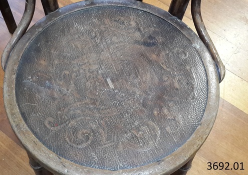 The round wooden seat has a carved floral pattern