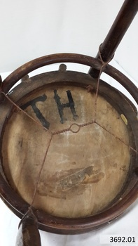 Inscriptions include hand painted 'T H' and a paper label. The legs are braced with a wooden ring and wire between the legs.