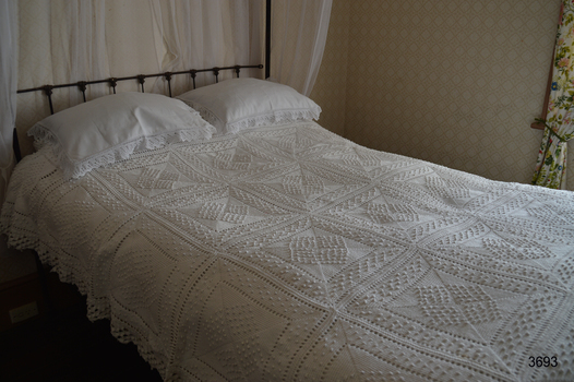 White crochet bedspread covers the double bed and down the sides
