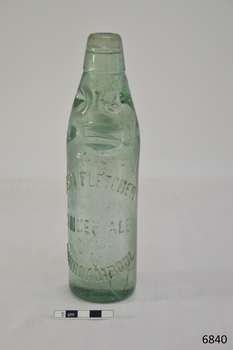 Clear bottle with marble seal, upright, glass has slight green tinge. Embossed text is clear.