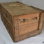 Oblong wooden trunk made from planks, with hinged lid on the long side. Rope handles on both short sides. Address of owner on lid.
