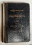 Black fabric covered hardcover with embossed gold text, covered in clear plastic