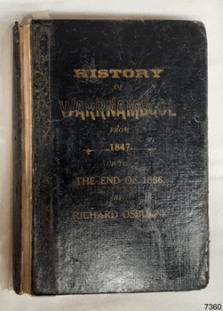 Black fabric covered hardcover with embossed gold text, covered in clear plastic