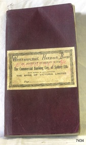 Maroon covered book with cream coloured label pasted on the front, printed and hand written details on label.