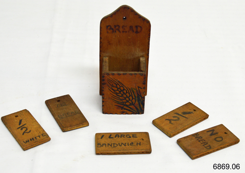 Wooden container surrounded by five wooden tiles with inscriptions