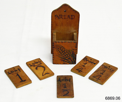 Inscriptions on tiles have numbers and text. A wheat sheaf motif is on the container.