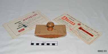 An oblong blotter with curved base and a handle on top. Two books of blotting paper also displayed, and sheets from them could be fitted onto the blotter for use.