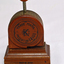 A bakelite and metal paper fastener. Round body with press handle at top.
