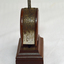 A bakelite and metal paper fastener. Round body with press handle at top.