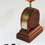 A bakelite and metal paper fastener. Round body with press handle at top.
