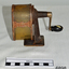  A metal desk pencil sharpener, with handle at rear, and aperture at front. Badly rusted.