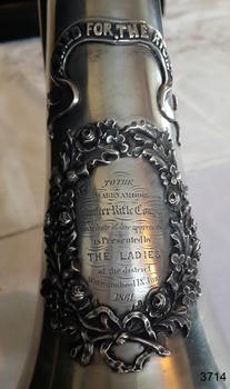 Engraved inscription is within a decorative oval floral wreath