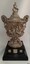Elaborately decorated silver trophy with lid on a black plinth with award shields on it