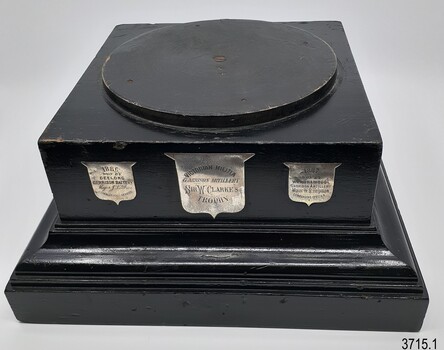 Square black glossy plinth with three silver engraved shields