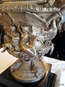 Two robed seated figures, one with a lyre. Oen-winged swan below handle.