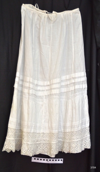Long petticoat, soft pleats at waist, fabric tie at back of waist, pin tucks around skirt, lace trim.