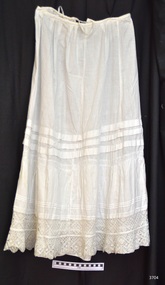 Long petticoat, soft pleats at waist, fabric tie at back of waist, pin tucks around skirt, lace trim.