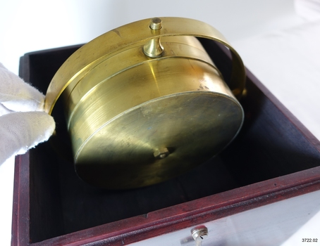 Side view of brass compass and gimbal within box