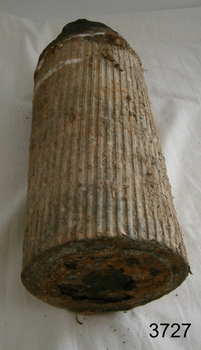 Cylinder shape ammunition shell with flat base and pointed tip. Vertical channels are around the side.