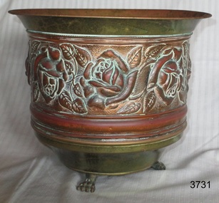 Copper jardiniere or plant pot, round, three feet, decorative floral design