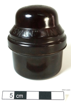 A small bottle of ink, sitting in a brown Bakelite screw top container, designed to protect it during travel.
