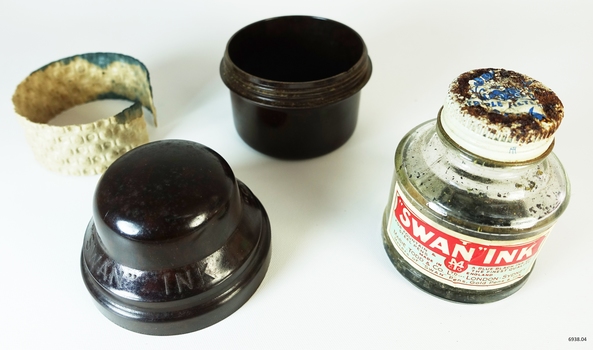 A small bottle of ink, sitting in a brown Bakelite screw top container, designed to protect it during travel.