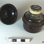 A small bottle of ink, sitting in a brown Bakelite screw top container, designed to protect it during travel.