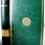 Emerald green hardcover book with gold border and round decal on front. Spine has embossed gold text