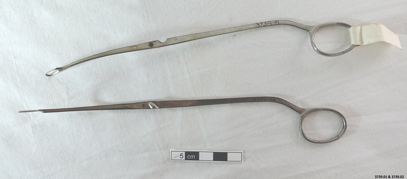 Stainless steel De Jardins stone holding forceps. There is a slight angle on the ends which are hollow. The separate parts fit together with a pin and hole and a clip clamps them shut.  