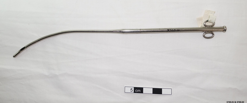 Stainless steel catheter with scissors like handles at one end of the curved instrument and an opening in the tube at the other end. The top and end of this instrument screw together.