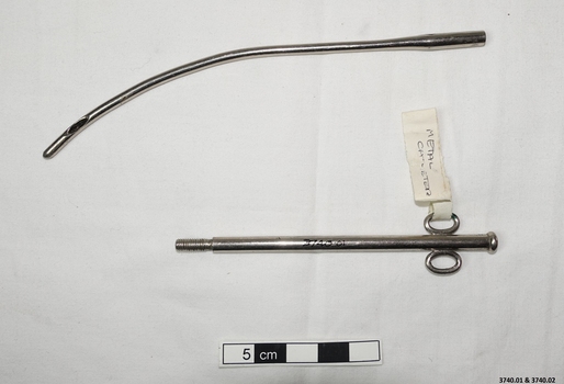 Stainless steel catheter with scissors like handles at one end of the curved instrument and an opening in the tube at the other end.