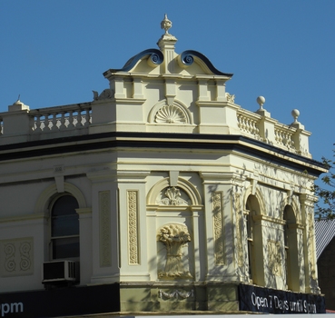 The sandstone building has intricate moulding, one representing a wheat sheaf