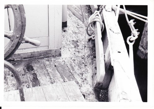 Black and white photograph of the condition of the deck near the ship's wheel