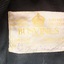 Cream fabric label with gold embroidered details and handwritten pen details